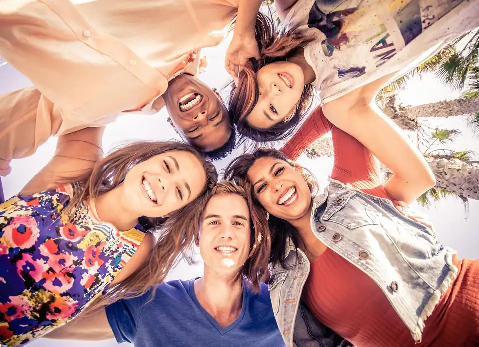 A group of people standing together in a circle, smiling